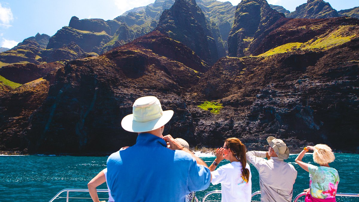 Tourists on a boat tour viewing the Napali Coast cliffs